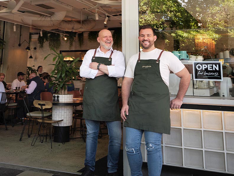 Two men stand outside the bakery