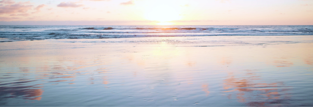 The sun is setting at the beach.